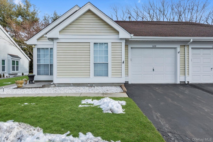 Single story home featuring driveway, an attached garage, a front yard, and roof with shingles