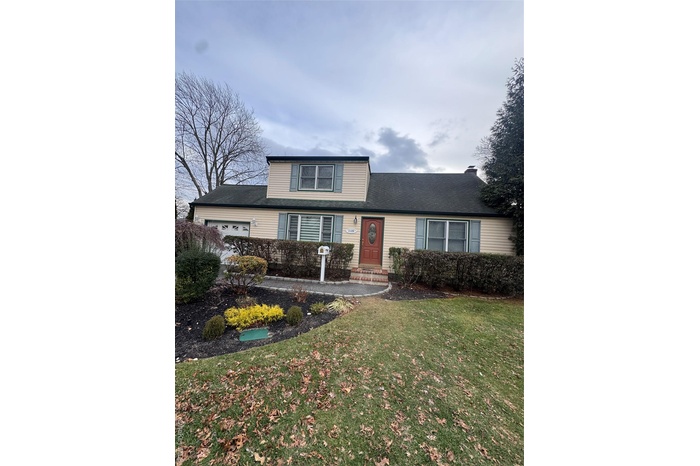 Traditional home featuring a garage, a front yard, and a shingled roof