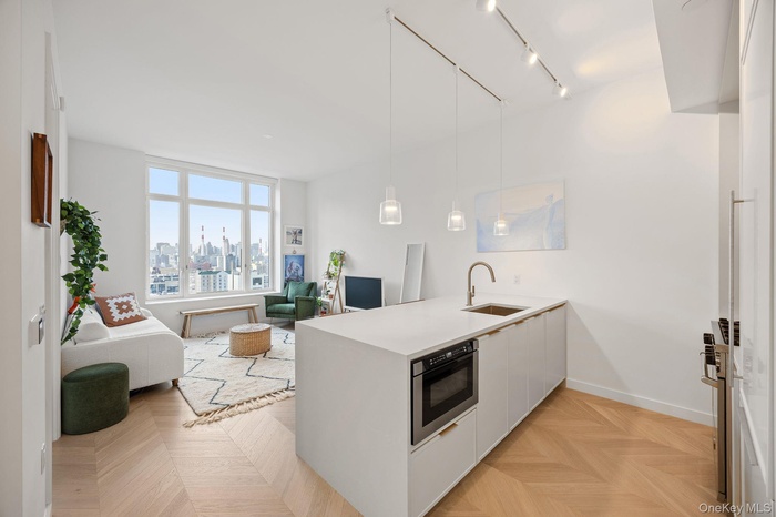 Kitchen featuring a peninsula, white cabinetry, pendant lighting, open floor plan, and light stone countertops