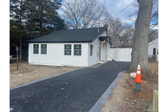 View of side of property with a chimney, roof with shingles, and driveway