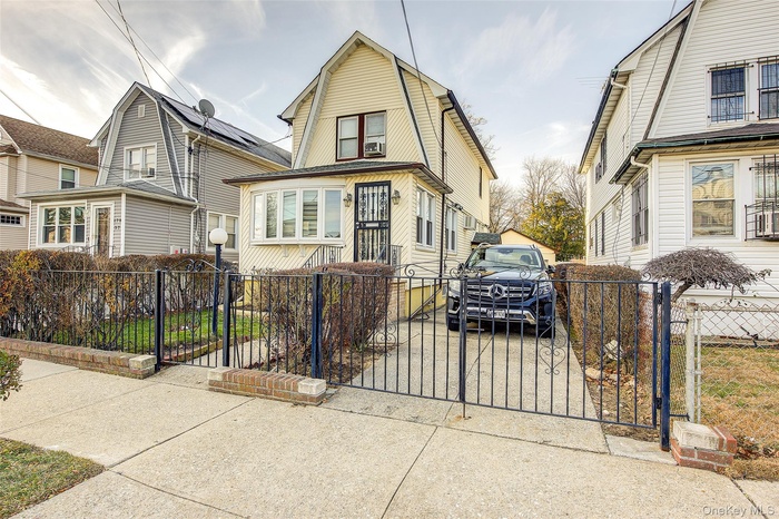 Colonial inspired home with a fenced front yard, a gate, and a gambrel roof