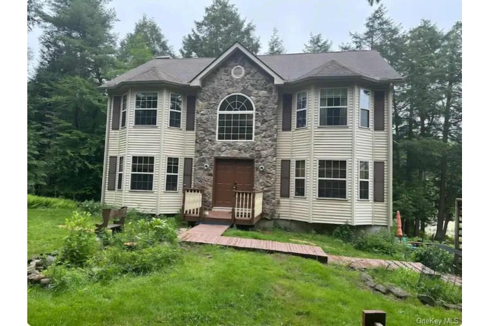 View of front of house featuring stone siding and a front yard