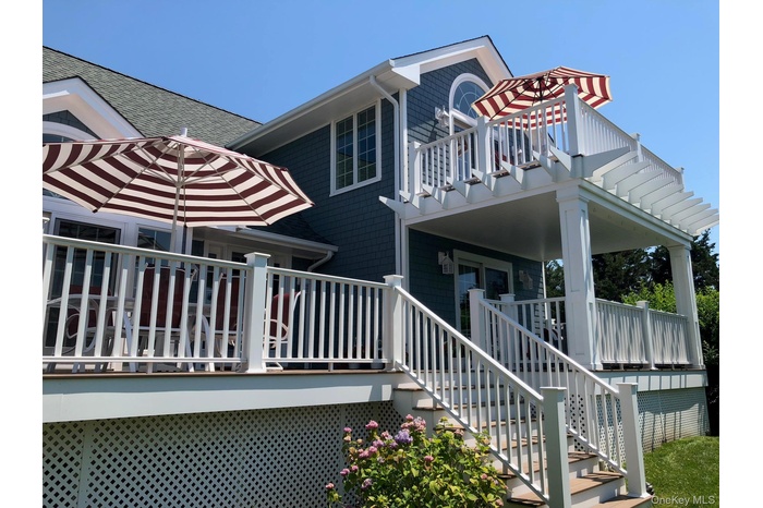 View of side of home featuring a shingled roof, a balcony, stairway, and covered porch