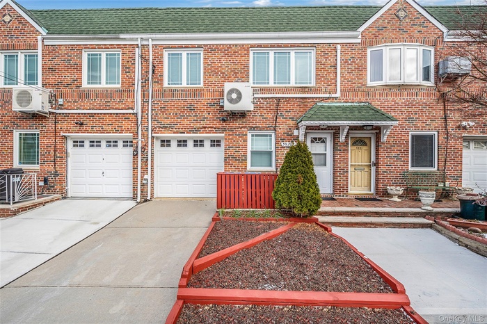 Traditional home featuring roof with shingles, concrete driveway, brick siding, and an attached garage