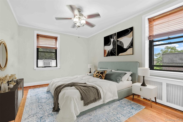 Bedroom with multiple windows, cooling unit, wood finished floors, and crown molding