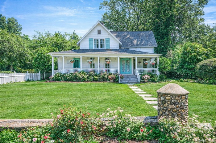 Farmhouse inspired home featuring a large porch and a shingled roof