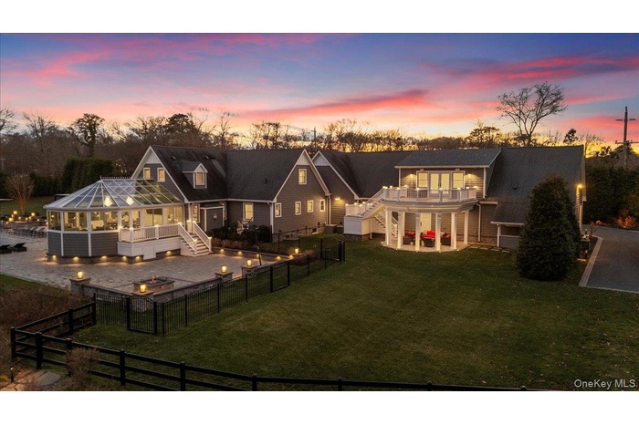 Back of house at dusk featuring stairs, a patio area, an outdoor fire pit, a fenced backyard, and a sunroom