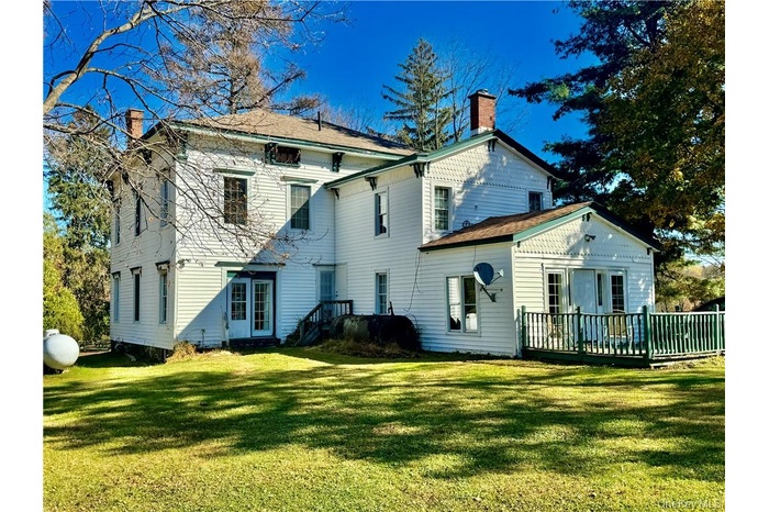 Rear view of house featuring a yard and a wooden deck