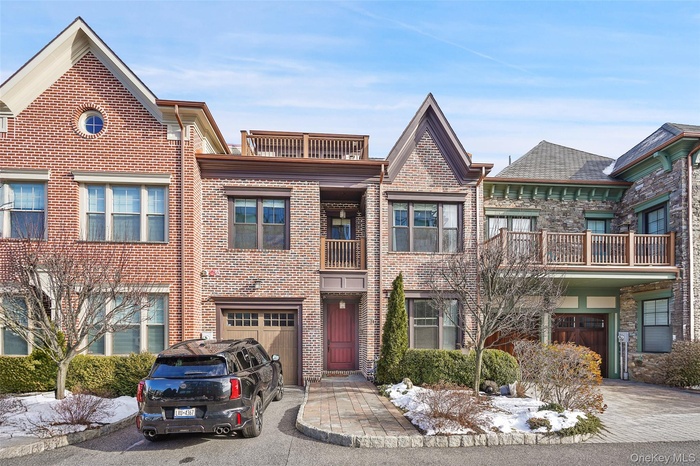 View of front of home featuring a balcony, brick siding, and driveway