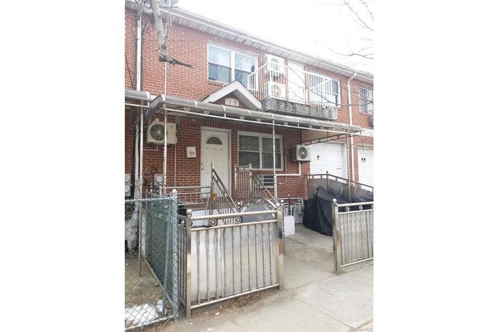 Traditional home featuring brick siding, a gate, a fenced front yard, and a balcony