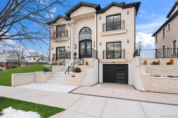 View of front of house with brick siding, driveway, a garage, and a balcony