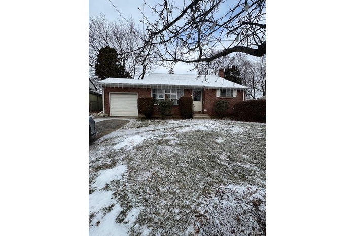 Ranch-style home with brick siding, a garage, and a chimney