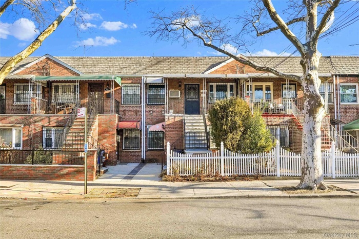 View of front of property with brick siding, a fenced front yard, and a shingled roof