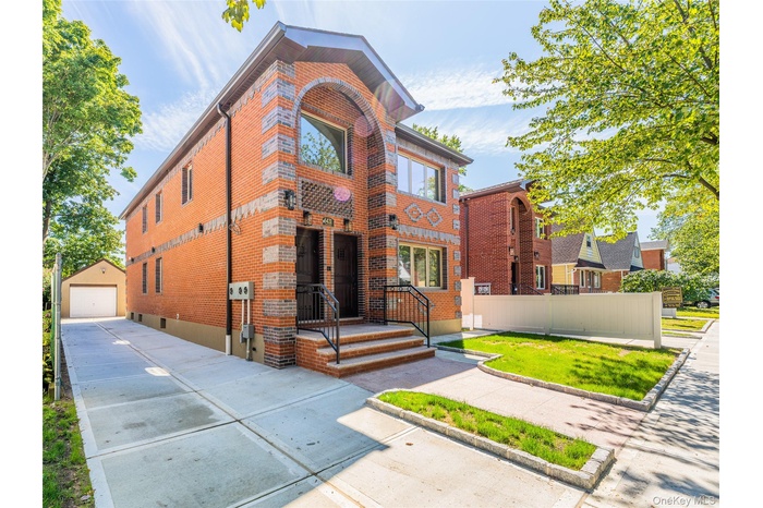 View of front of home featuring brick siding, an outdoor structure, a detached garage, and a front lawn