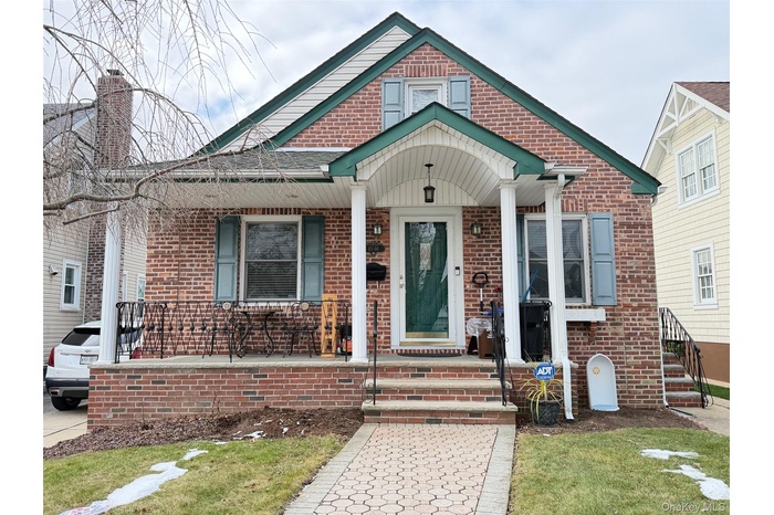 View of front of home with brick siding, covered porch, and a front yard