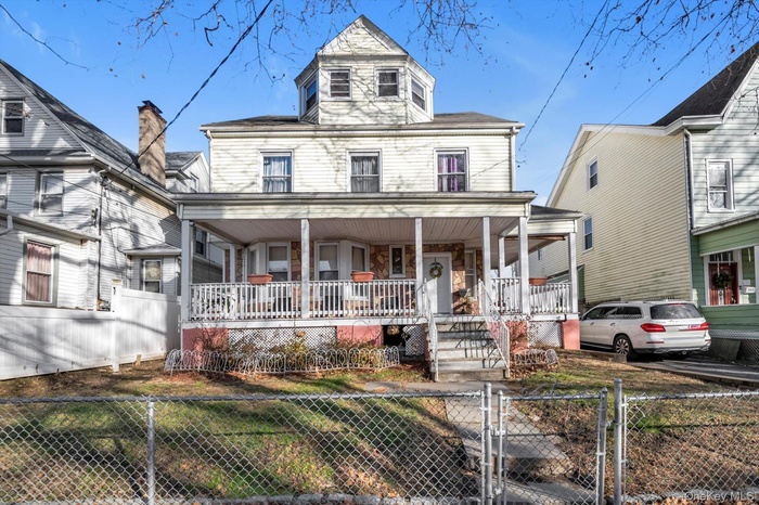 View of front of house with a gate, a fenced front yard, a porch, and stairs