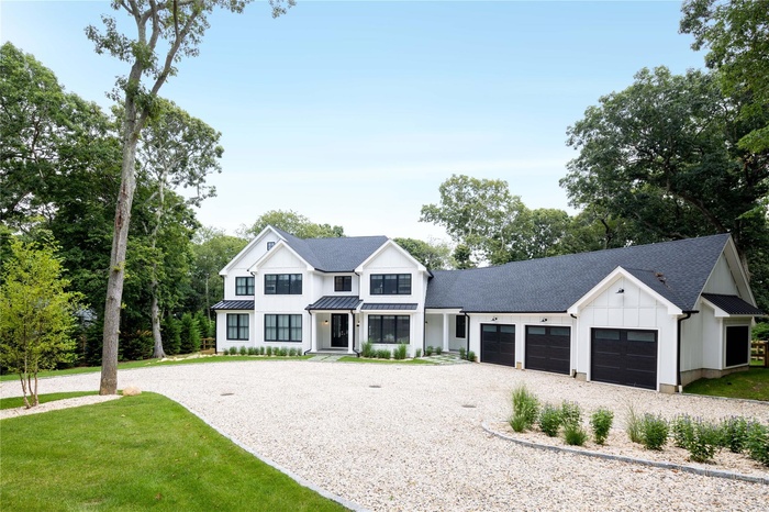 Modern inspired farmhouse with board and batten siding, gravel driveway, an attached garage, a standing seam roof, and roof with shingles