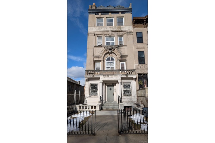 View of front of property with a fenced front yard, a gate, and stone siding