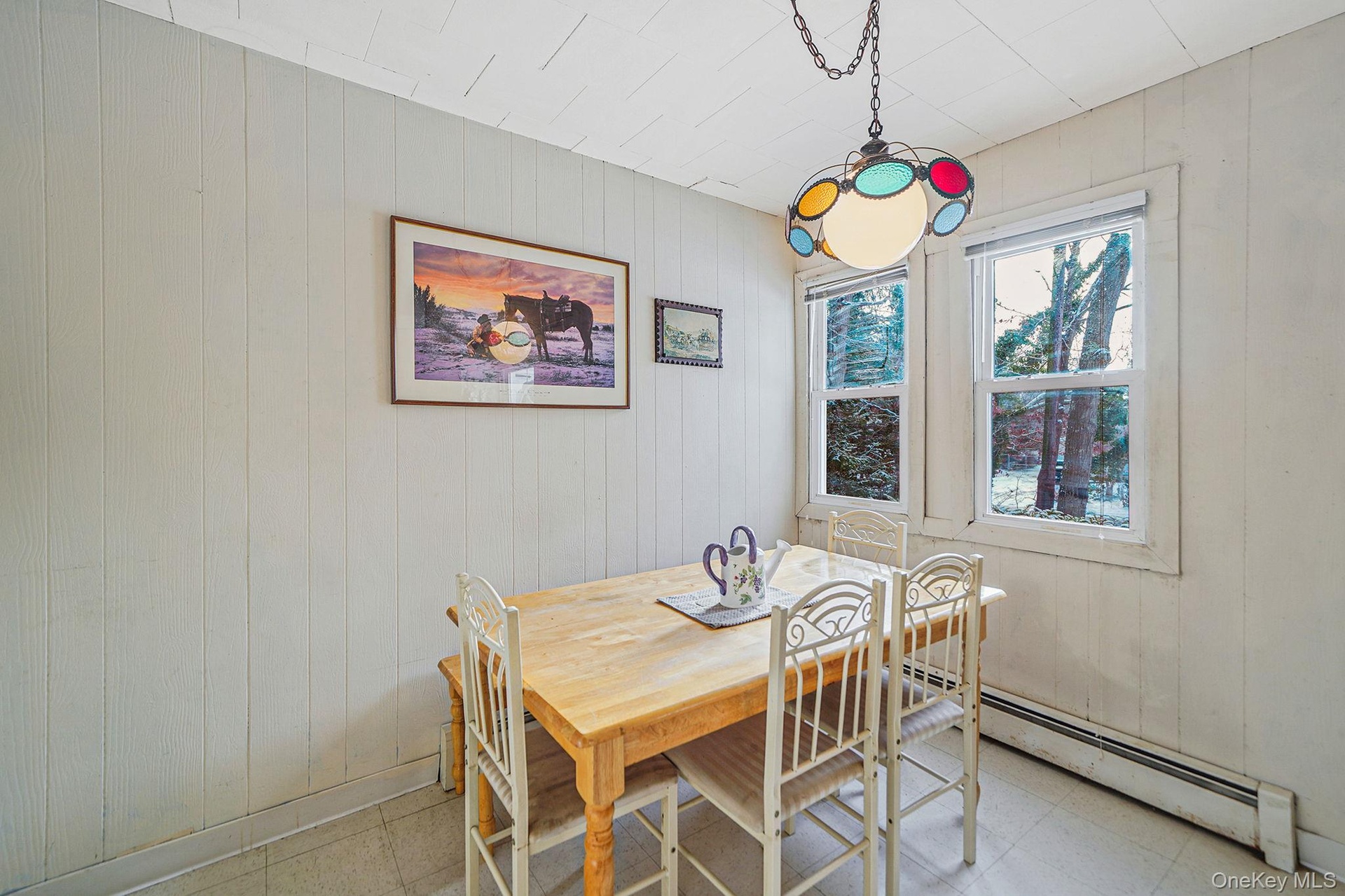 Dining space featuring wooden walls, tile patterned floors, and a baseboard heating unit