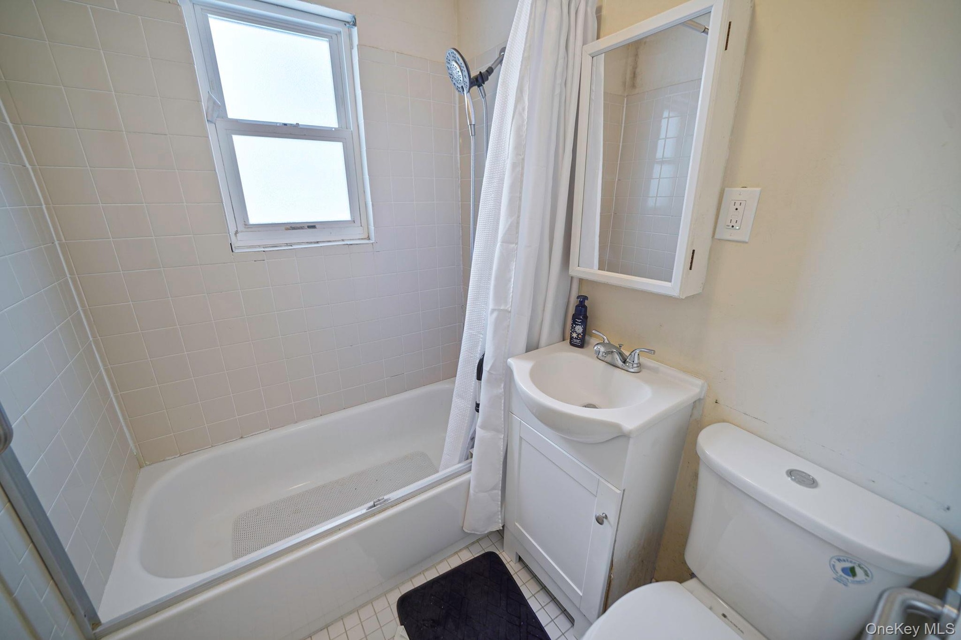 Full bathroom with vanity, shower / bathtub combination with curtain, and tile patterned floors