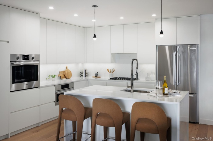 Kitchen with modern cabinets, appliances with stainless steel finishes, decorative light fixtures, white cabinetry, and recessed lighting