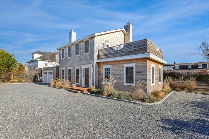 Rear view of property with a chimney, driveway, and a garage