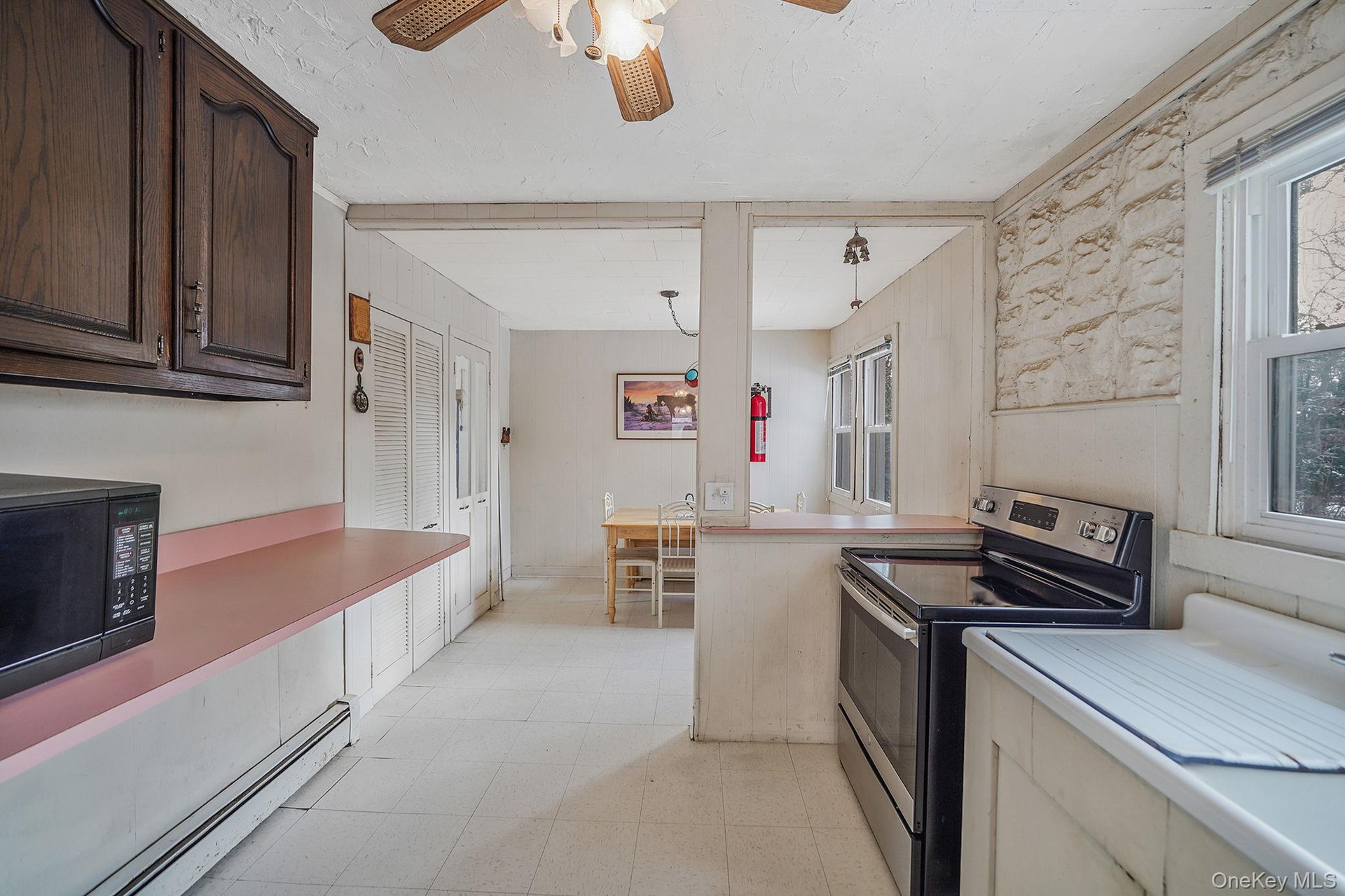 Kitchen featuring stainless steel electric range, a baseboard radiator, light countertops, light flooring, and black microwave