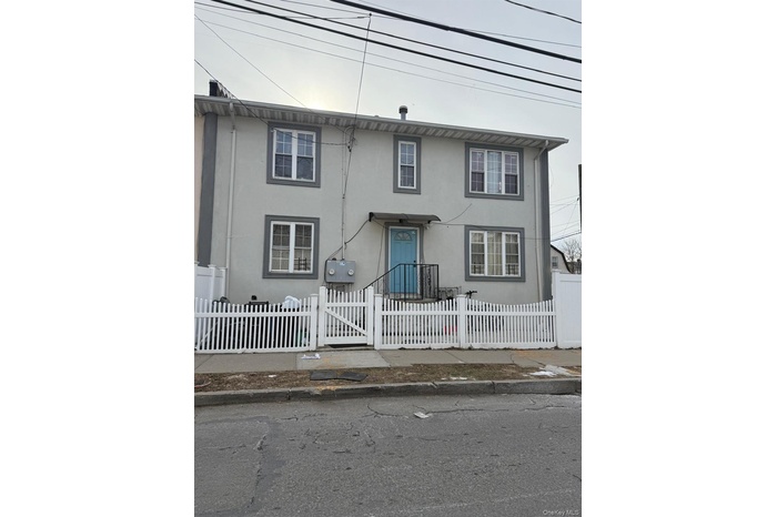 Traditional-style house featuring stucco siding, a fenced front yard, and a gate