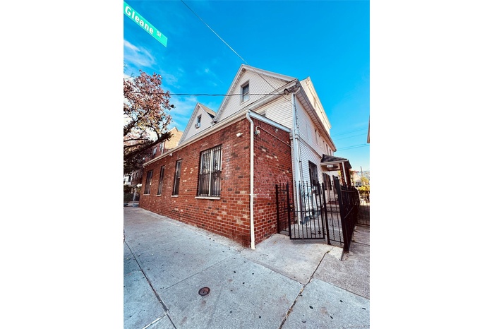 View of side of property with brick siding and a gate