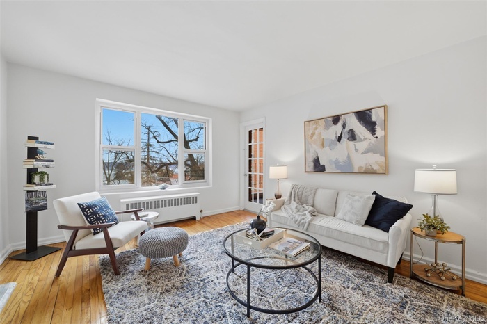 Bright living room with hardwood floors and seamless access to a private balcony showcasing Hudson River views.