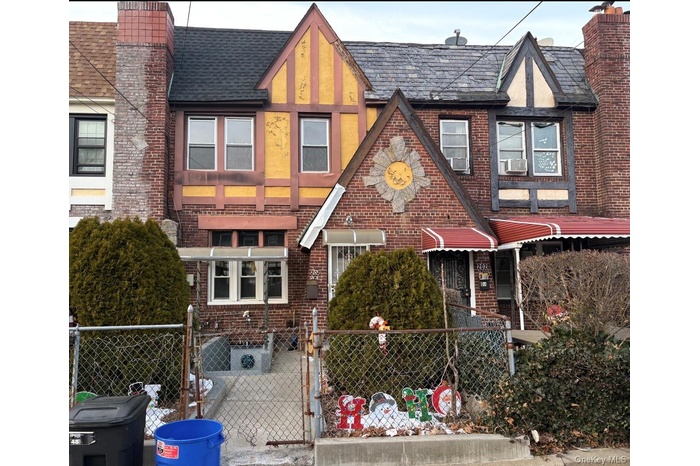 Tudor home with brick siding, a gate, and a chimney