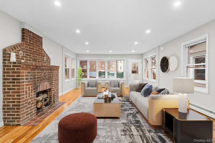 Living room with wood finished floors, recessed lighting, a fireplace, and a baseboard heating unit