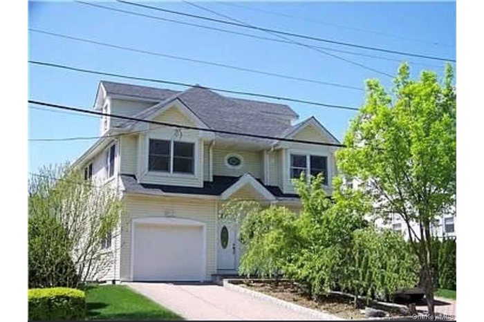 View of front facade with concrete driveway and an attached garage