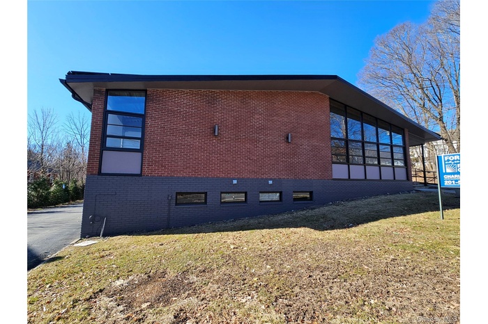 View of side of property featuring a lawn and brick siding