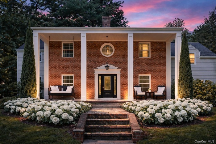 View of front of home with a porch, a chimney, and brick siding