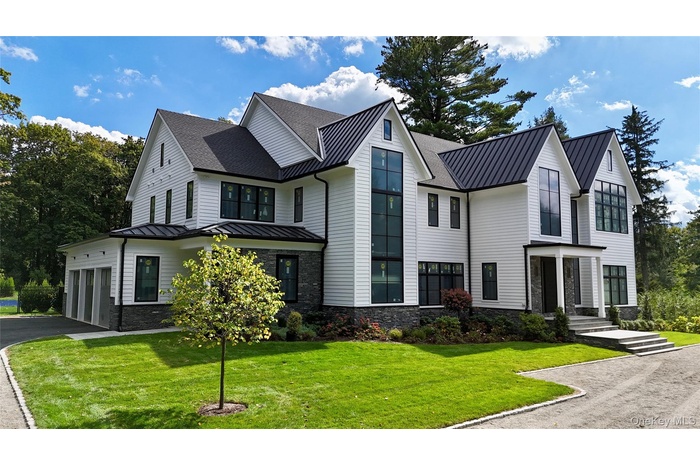Modern farmhouse style home with a standing seam roof, a metal roof, stone siding, and a front yard