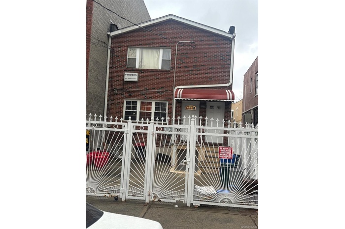 View of front of home featuring brick siding, a fenced front yard, and a gate