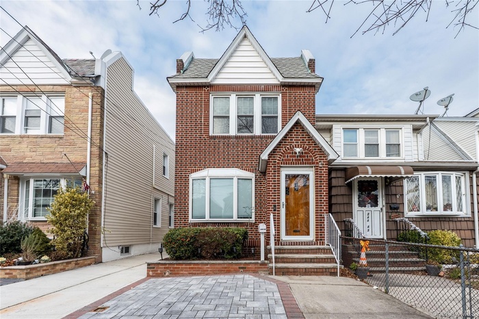 View of front facade with roof with shingles and brick siding