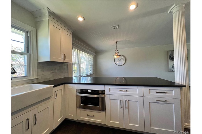 Kitchen with white cabinetry, a peninsula, oven, pendant lighting, and backsplash