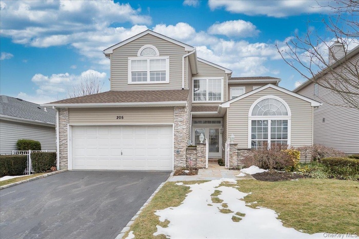 Traditional home with driveway, stone siding, a garage, and a shingled roof
