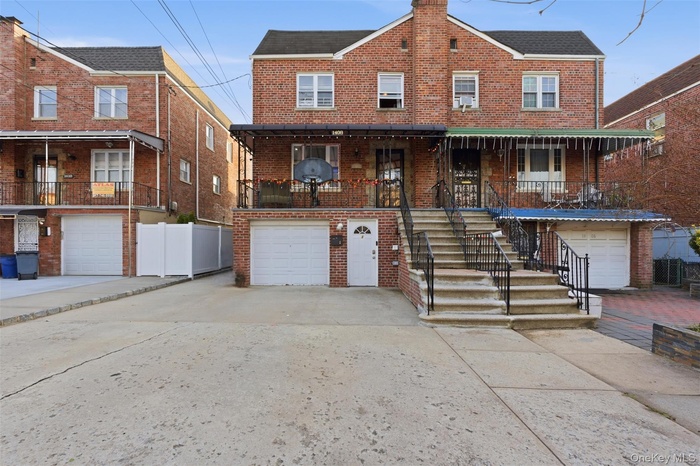 View of front of property featuring brick siding, concrete driveway, an attached garage, a balcony, and stairway