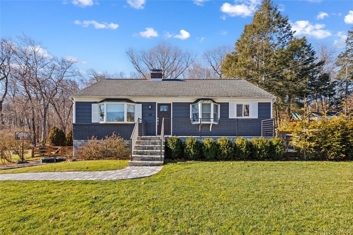 Ranch-style home featuring a front lawn, a chimney, and roof with shingles