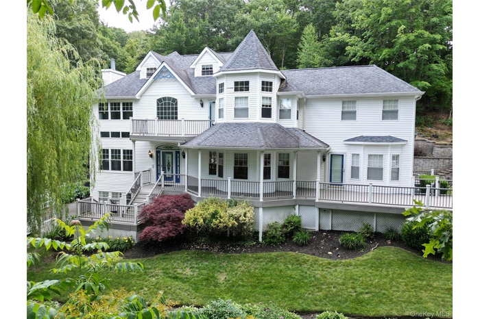 Victorian-style house featuring a shingled roof, a porch, and a front lawn