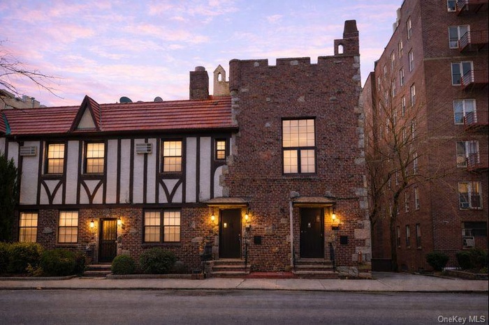 View of front facade at dusk featuring brick siding