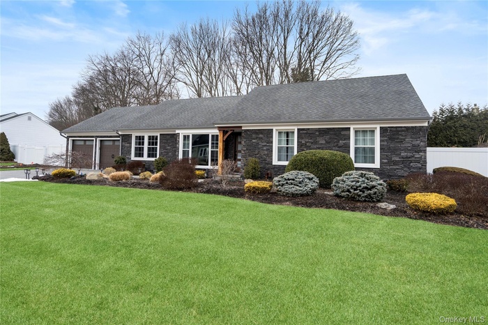 Ranch-style house with stone siding, a garage, and roof with shingles