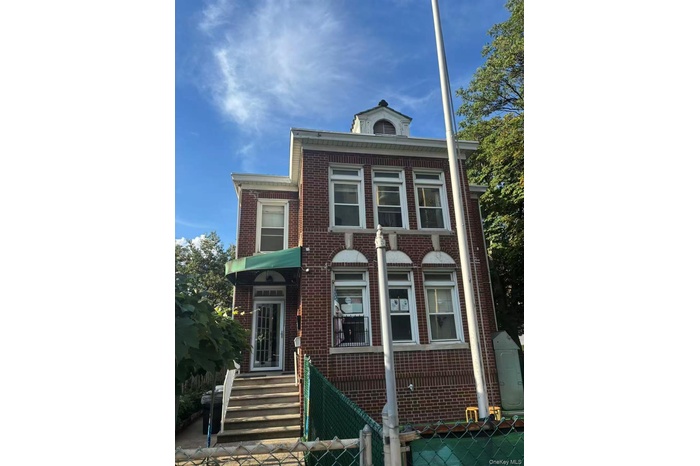 View of front facade featuring brick siding, a fenced front yard, and a gate