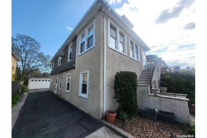 View of side of property featuring stucco siding, a garage, and stairway