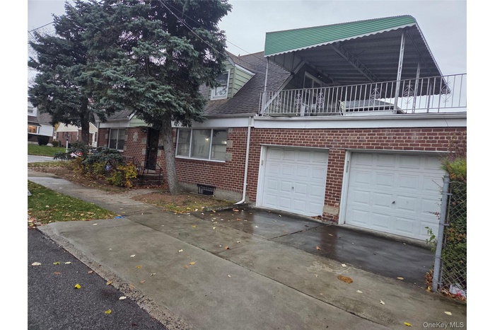View of front of house with driveway, brick siding, a garage, and roof with shingles