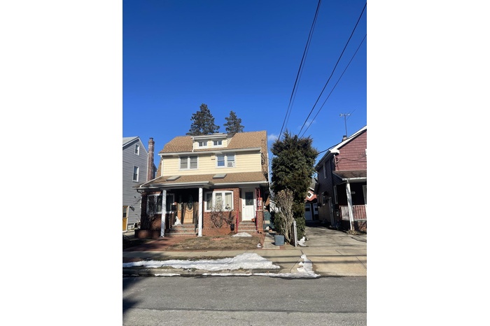 Traditional style home with covered porch, brick siding, and roof with shingles
