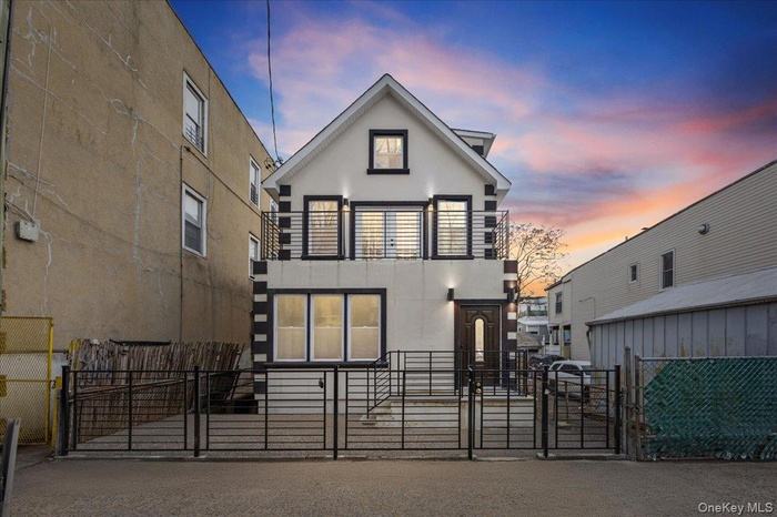View of front facade with a gate, stucco siding, a fenced front yard, and a balcony